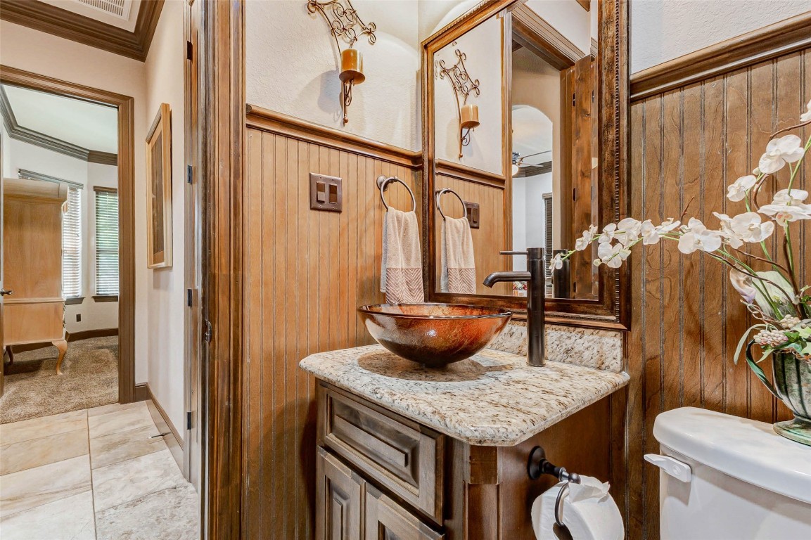 4315 Wickby Street Fulshear, TX 77441 - Photo 21 of 46 Powder bathroom with rustic wood paneling and elegant fixtures is conveniently located for guest use. It features a unique vessel sink on a granite countertop and a framed mirror.