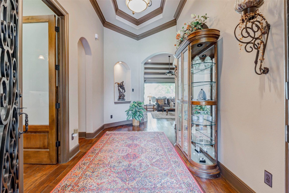4315 Wickby Street Fulshear, TX 77441 - Photo 5 of 46 Beautifully designed entryway featuring a high ceiling with crown molding and elegant lighting. Arched openings lead to a cozy living area with large windows, enhancing the inviting atmosphere.