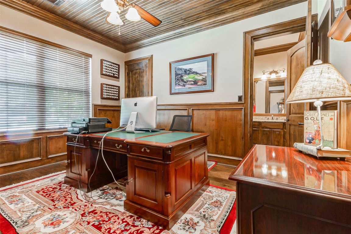4315 Wickby Street Fulshear, TX 77441 - Photo 6 of 46 Sophisticated home office featuring rich wood paneling, ceiling and flooring. The room is well-lit and includes a doorway leading to an adjacent bathroom.