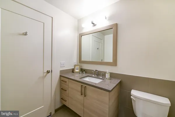 a bathroom with a granite countertop toilet sink and mirror