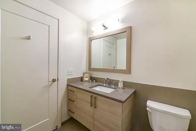 a bathroom with a granite countertop toilet sink and mirror