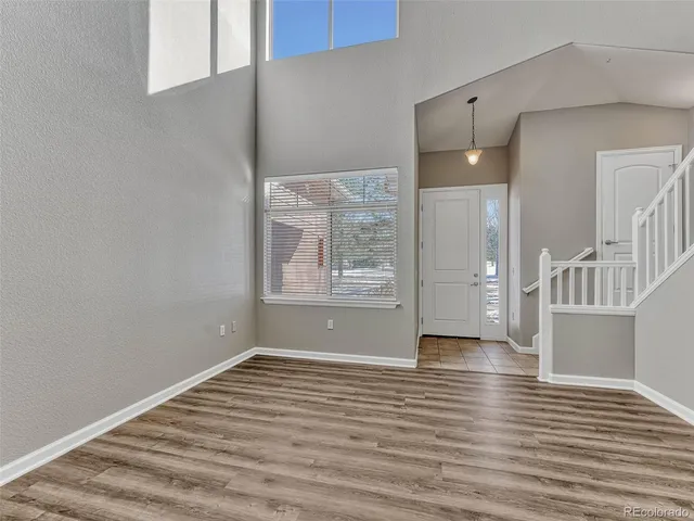 a view of an empty room with window and wooden floor