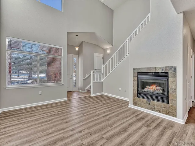 a view of an empty room with wooden floor fireplace and a window
