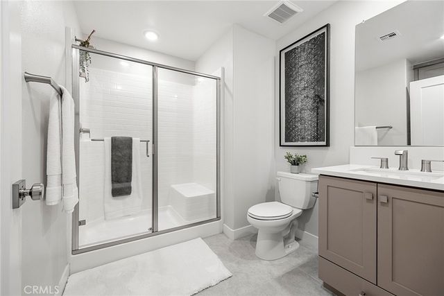 a bathroom with a shower sink vanity mirror and toilet