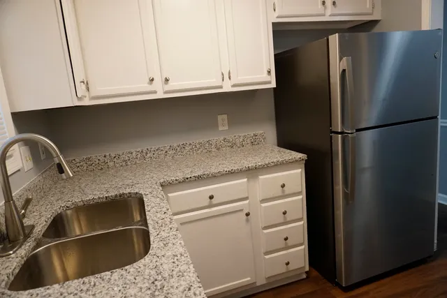 a kitchen with granite countertop white cabinets and refrigerator