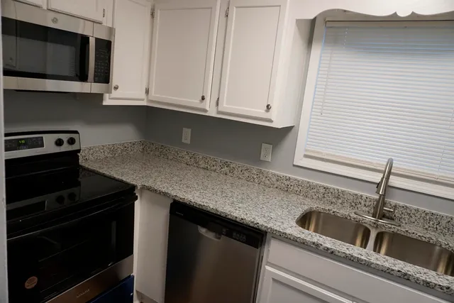 a kitchen with granite countertop white cabinets and a stove