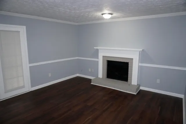 a view of an empty room with wooden floor and a fireplace