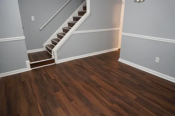 a view of an empty room with wooden floor and stairs
