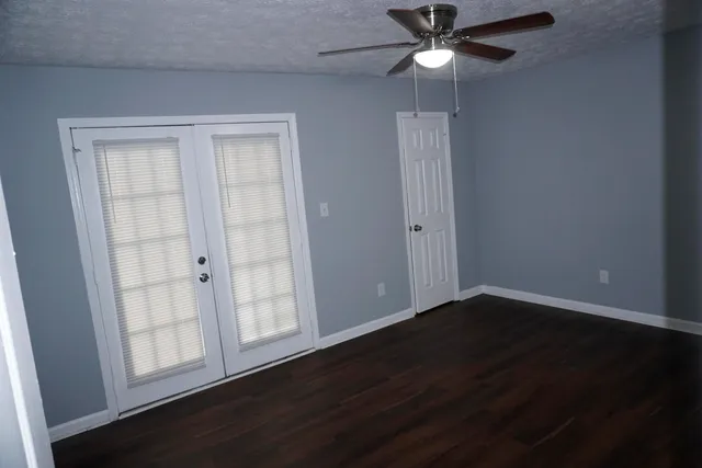 an empty room with wooden floor closet and fan
