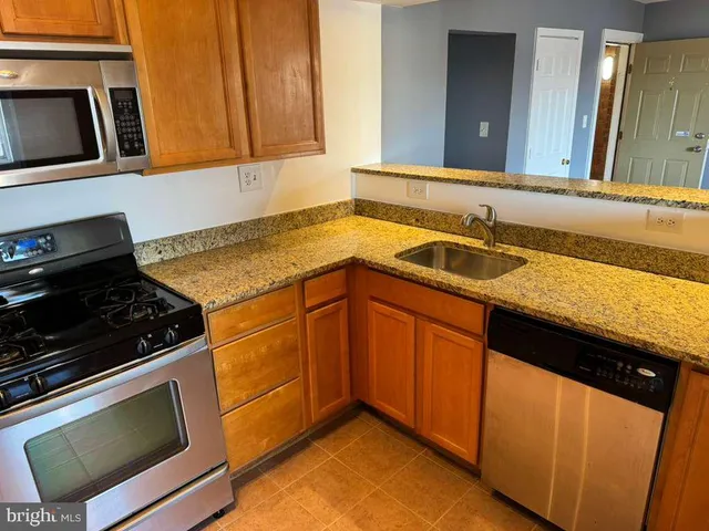 a kitchen with granite countertop cabinets and steel stainless steel stove next to a sink