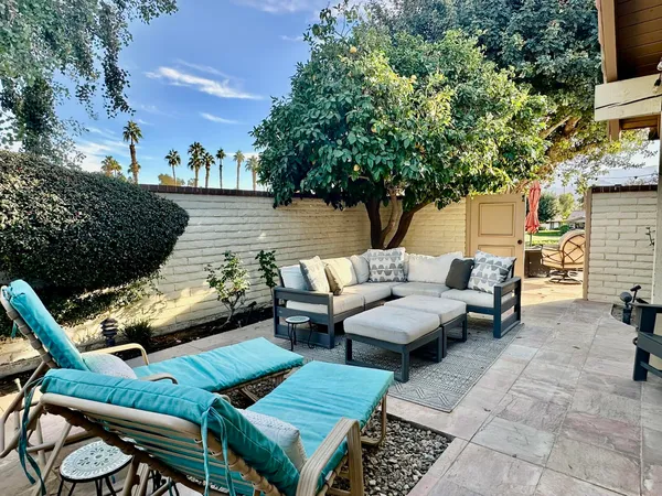 a view of a patio with couches table and chairs and potted plants