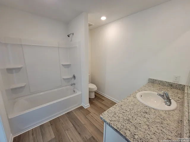 a bathroom with a granite countertop sink a toilet and bathtub