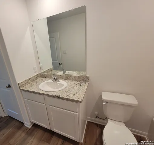a bathroom with a granite countertop toilet and a sink