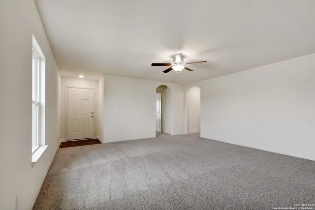 a view of an empty room with a chandelier fan