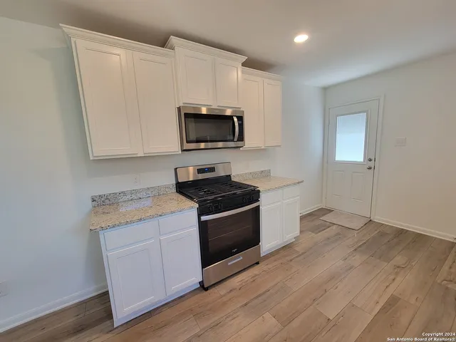 a kitchen with granite countertop cabinets stainless steel appliances and wooden floor
