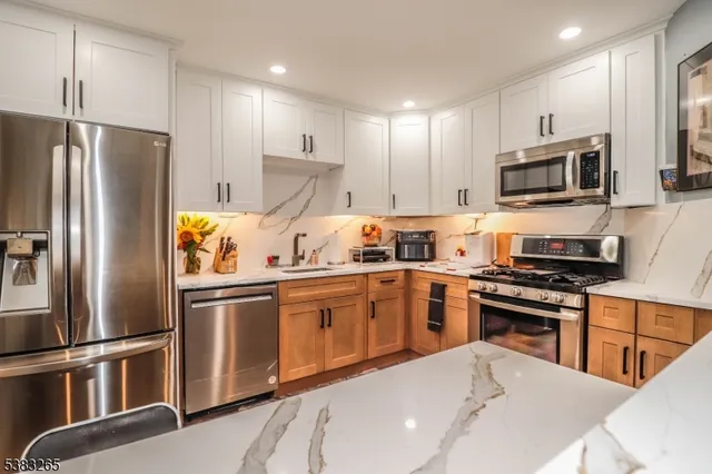 a kitchen with stainless steel appliances granite countertop a refrigerator a stove top oven a sink and dishwasher