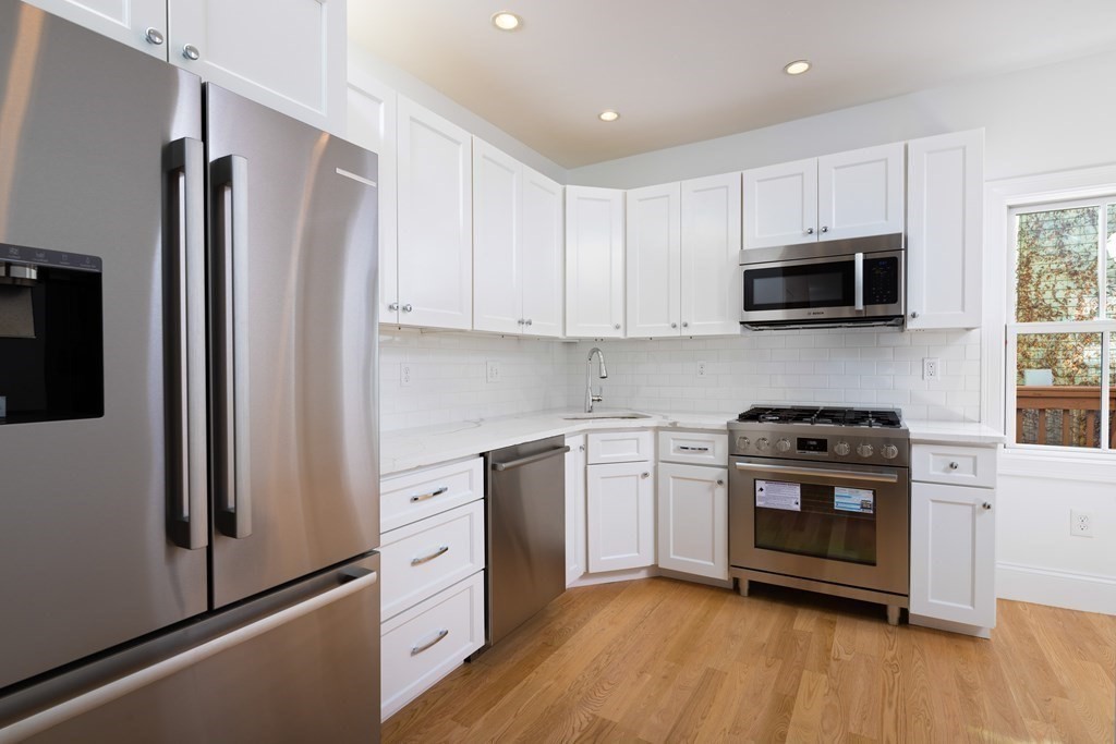 a kitchen with white cabinets stainless steel appliances and wooden floor