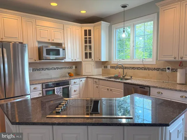 a kitchen with kitchen island granite countertop a stove a sink and a refrigerator