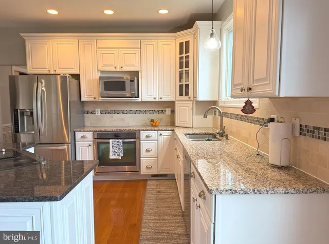 a kitchen with stainless steel appliances granite countertop a sink a stove and a refrigerator