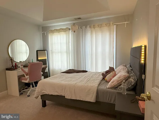 a bedroom with a bed chair and large windows