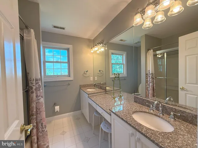a bathroom with a granite countertop double vanity sink and a mirror
