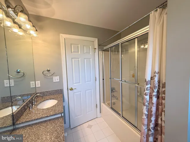 a bathroom with a granite countertop shower and a sink