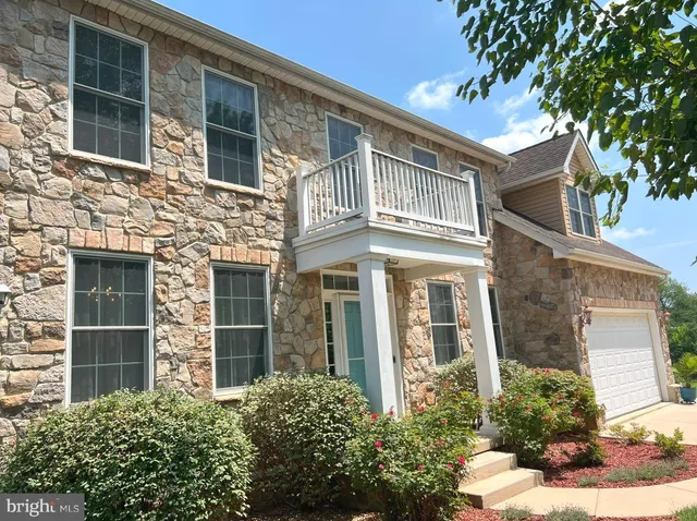front view of a brick house with a large windows and a flower plants