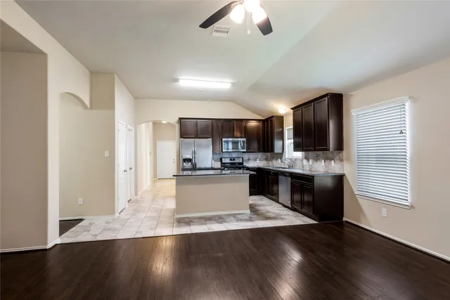 a large kitchen with a center island and wooden floor