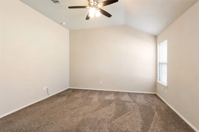 an empty room with a window and ceiling fan