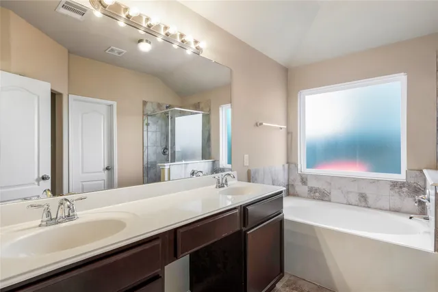 a bathroom with a tub double sink and a mirror