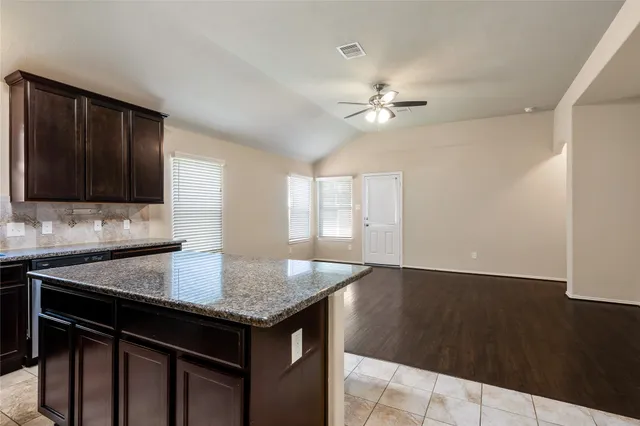 a kitchen with granite countertop a sink cabinets and stainless steel appliances