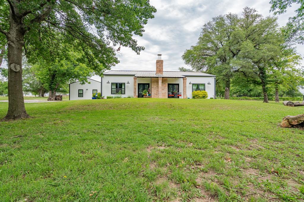 View of front of home featuring a front yard, a chimney, and a standing seam roof