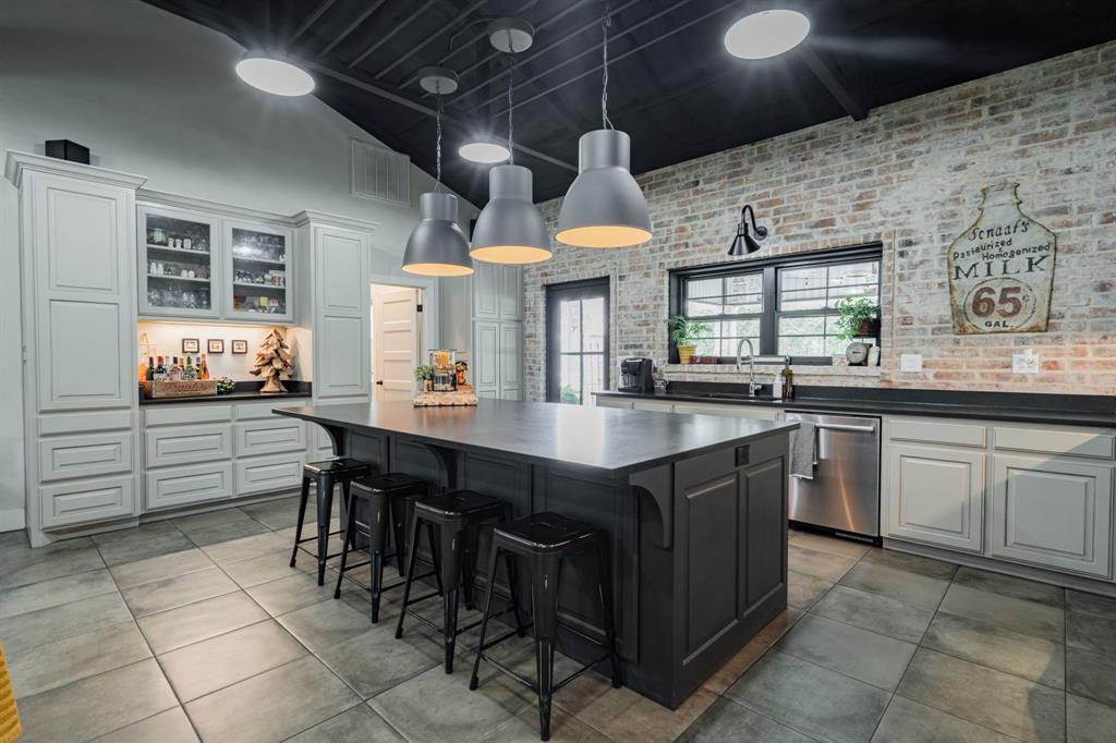 853 County Road 2215 Decatur, TX 76234 - Photo 10 of 39 Two tone kitchen with brick wall, hanging light fixtures, dishwasher, a kitchen island, and a kitchen bar