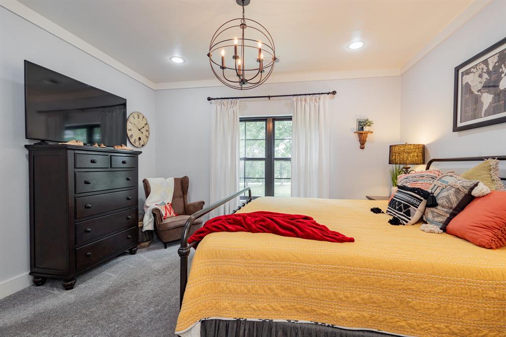 853 County Road 2215 Decatur, TX 76234 - Photo 12 of 39 Primary bedroom with crown molding, light colored carpet, and a chandelier