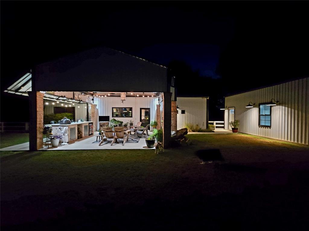 853 County Road 2215 Decatur, TX 76234 - Photo 28 of 39 Back of house at night with a patio area, exterior kitchen, and a lawn