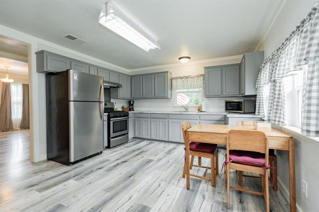 853 County Road 2215 Decatur, TX 76234 - Photo 32 of 39 Kitchen in guest house with stainless steel appliances, gray cabinetry, light countertops, crown molding, and light wood-type flooring