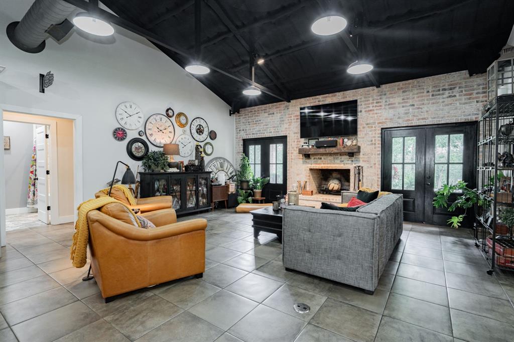 853 County Road 2215 Decatur, TX 76234 - Photo 7 of 39 Living room featuring brick wall, french doors, light tile patterned floors, and vaulted ceiling