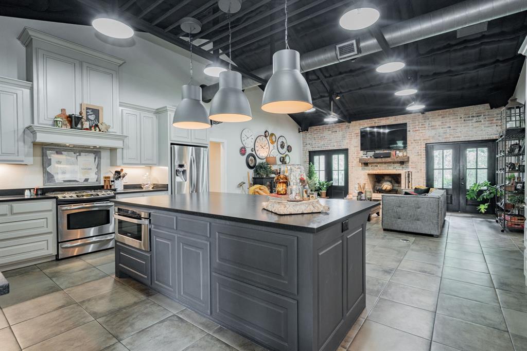 853 County Road 2215 Decatur, TX 76234 - Photo 38 of 39 Kitchen featuring brick wall, stainless steel appliances, open floor plan, hanging light fixtures, and a kitchen island