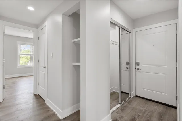 an empty room with wooden floor closet and windows