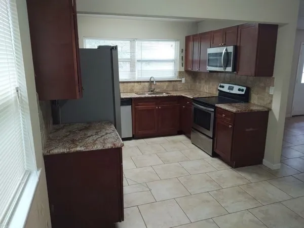 a kitchen with granite countertop a refrigerator and a stove top oven