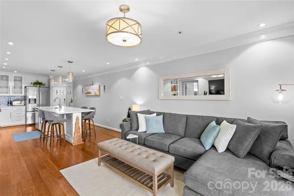 a living room with furniture kitchen view and a wooden floor