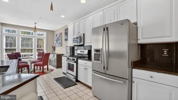 a kitchen with stainless steel appliances granite countertop a sink a stove top oven a refrigerator with white cabinets and black appliances