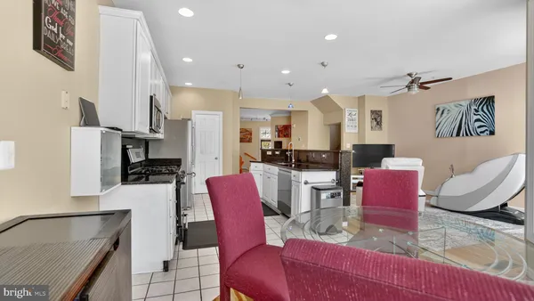 a kitchen with stainless steel appliances granite countertop a dining table chairs refrigerator and sink