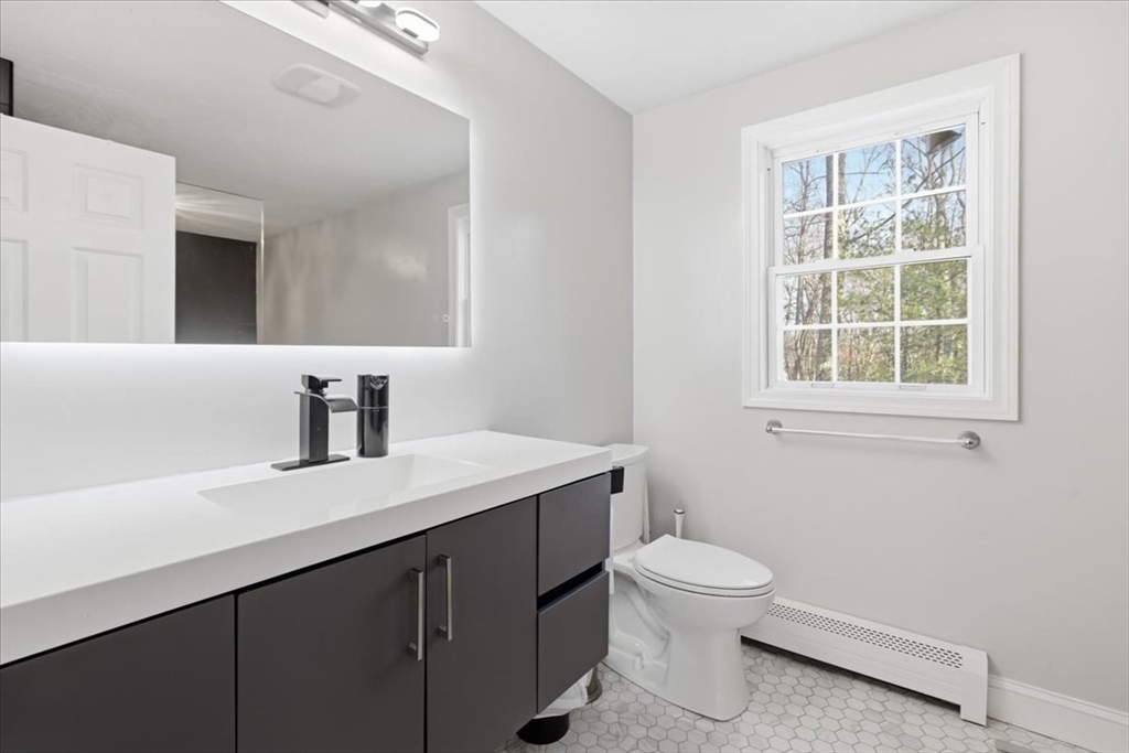 133 Grove Street Bellingham, MA 02019 - Photo 33 of 42 a bathroom with a granite countertop sink a toilet and a window