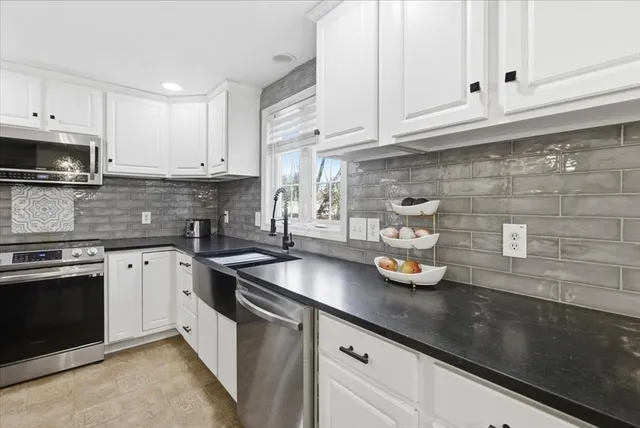 a kitchen with stainless steel appliances granite countertop a sink a stove and white cabinets