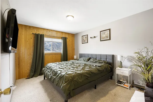 a bedroom with a bed and a potted plant next to a window