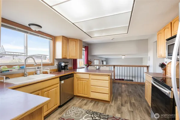 a kitchen with stainless steel appliances granite countertop a sink a stove cabinets counter space and a window