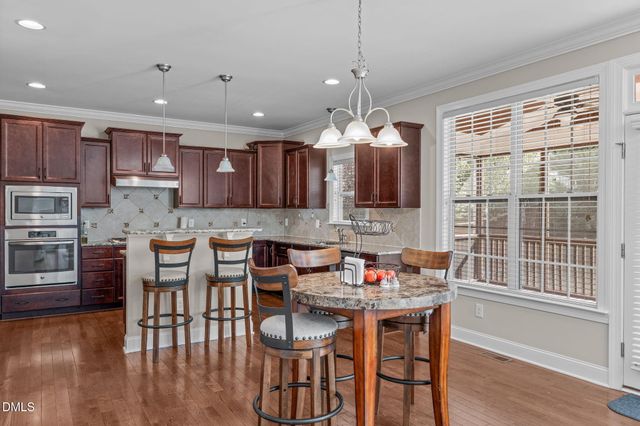 a kitchen with stainless steel appliances granite countertop wooden cabinets a dining table and chairs