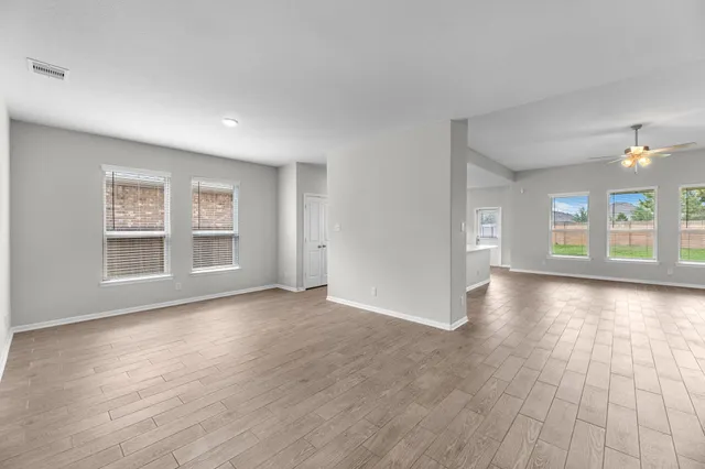 a view of a big room with wooden floor and windows