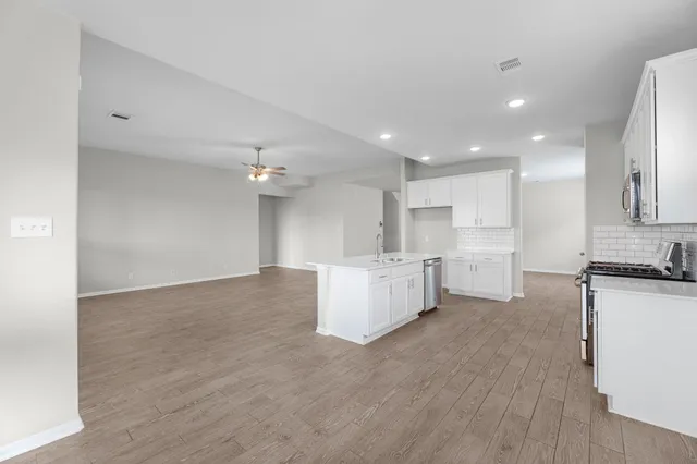 a view of kitchen with kitchen island white cabinets and stainless steel appliances